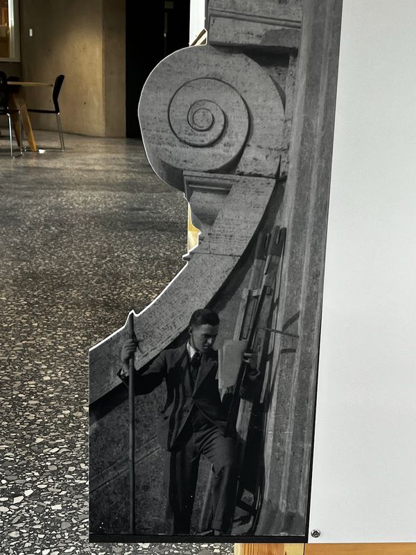 Photographic cut-out of a figure beside a stone volute
